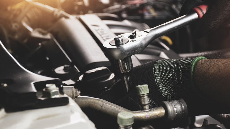 엔진에 소켓 렌치를 사용하는 사람