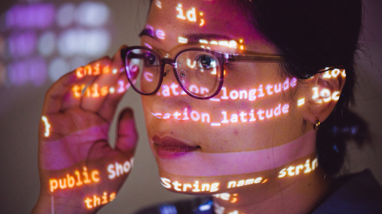 그녀의 얼굴에 투사 된 프로그램 코드를 가진 여성 프로그래머의 초상화