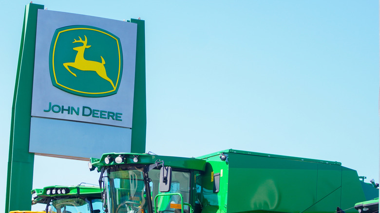 여러 녹색 중장비 기계 옆에있는 John Deere 대리점 간판