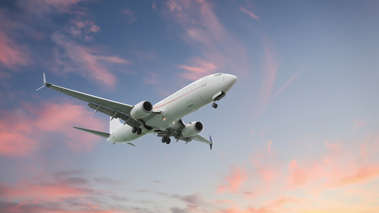 일몰에 구름이있는 아름다운 하늘에서 비행기가 날아가는 비행기.