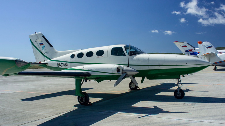 푸른 하늘 아래 활주로에 흰색과 녹색 세스나 402b