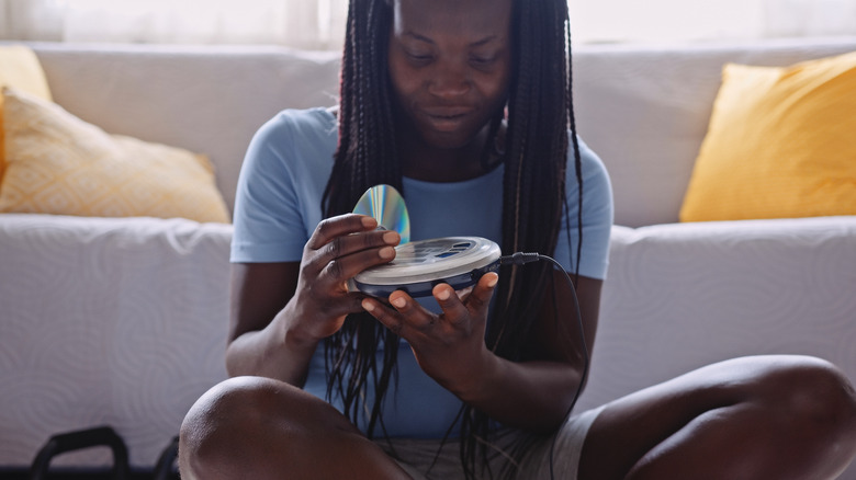 보조 케이블을 연결하여 CD를 휴대용 소니 CD 플레이어에로드하는 사람.