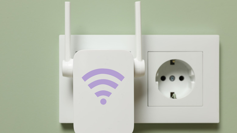 가벼운 녹색 벽에 소켓에 플러그 된 Wi-Fi 기호가있는 새로운 현대 리피터