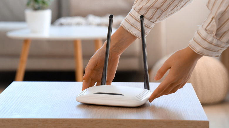 테이블 위에 Wi-Fi 라우터를 배치하는 사람.