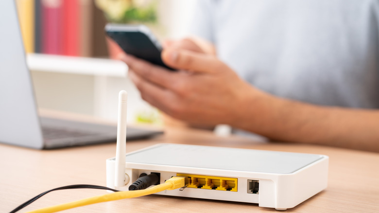 라우터 옆에 전화와 노트북을 사용하는 사람