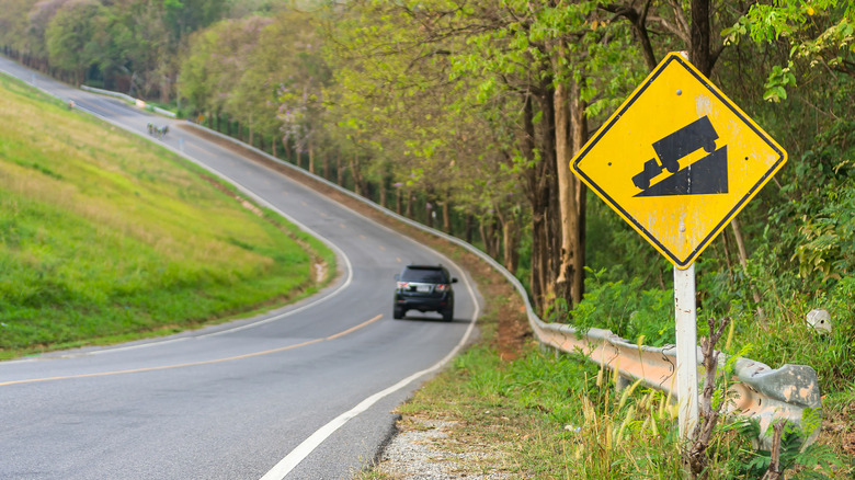 자동차가있는 구불 구불 한 도로 옆에 가파른 경사 사인