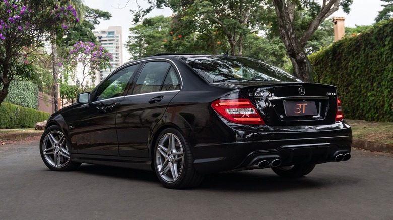 교외 거리에서 검은 메르세데스-벤츠 C63 AMG의 후면 3/4 전망