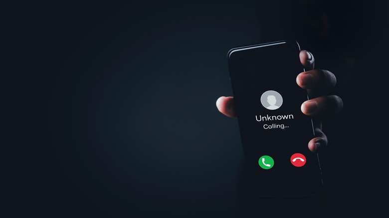 알 수없는 발신자 알림으로 휴대 전화를 손으로 잡고 있습니다