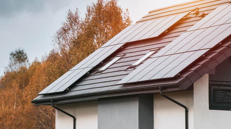 태양 전지판과 가을 나무가있는 현대 집의 사진.