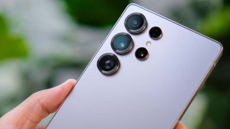 삼성 갤럭시 S25 울트라는 녹색이 흐릿한 배경 앞에서 누군가가 잡고 있습니다.