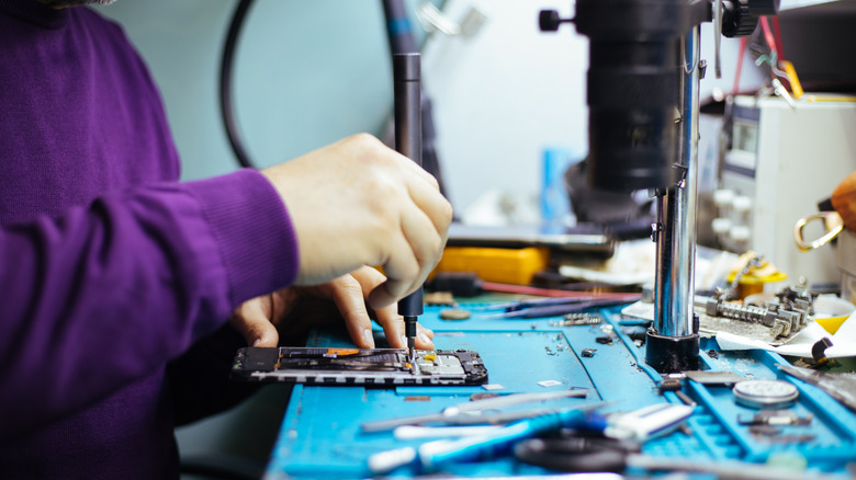 기술자가 드라이버로 스마트 폰을 분해합니다.