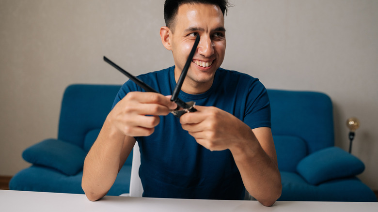 안테나를 연결하여 Wi-Fi 모듈을 조립하는 미소 기술자 남성의 초상화