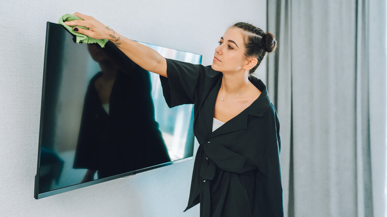 TV 상단을 먼지하는 여성