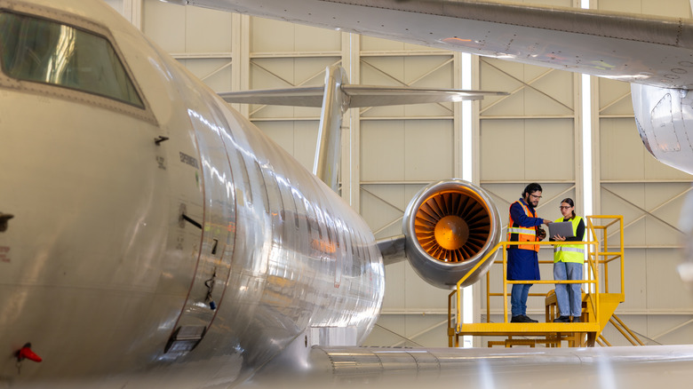 두 엔지니어는 여객 제트의 동체를 검사합니다