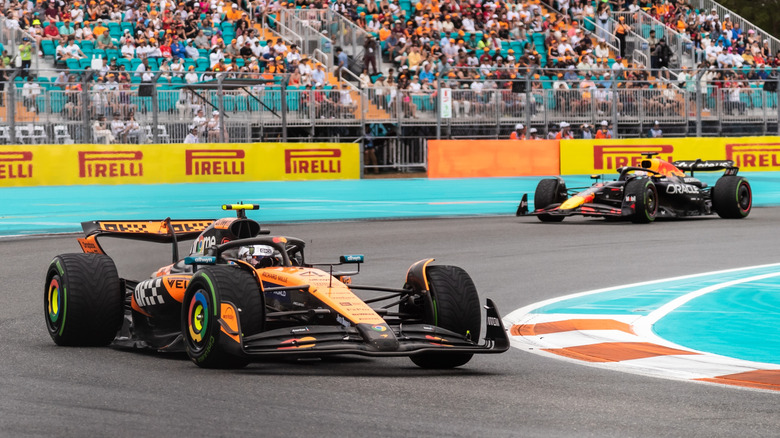 Lando Norris는 Red Bull을 배경으로 McLaren F1 자동차를 운전하여 모퉁이를 돌고 있습니다.