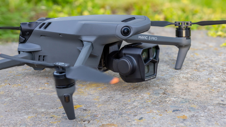 DJI Mavic 3 Pro가 녹지를 배경으로 거친 표면 위에 앉아 있는 사진