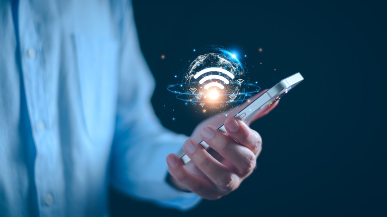 거품 속에 떠다니는 WIFI 그래픽이 있는 전화기를 들고 있는 사람