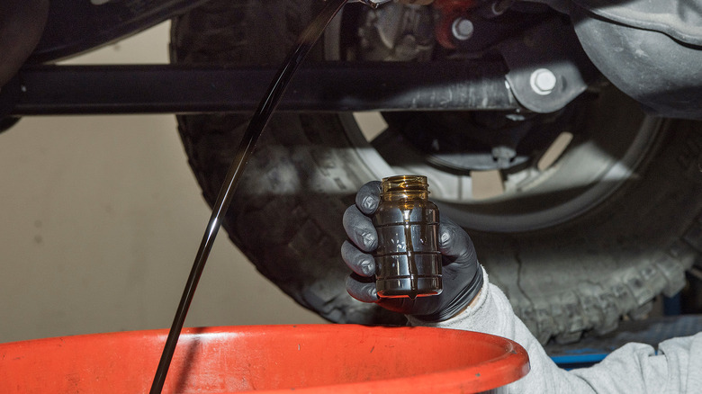 배출되는 자동차 오일 샘플을 채취하는 과학자