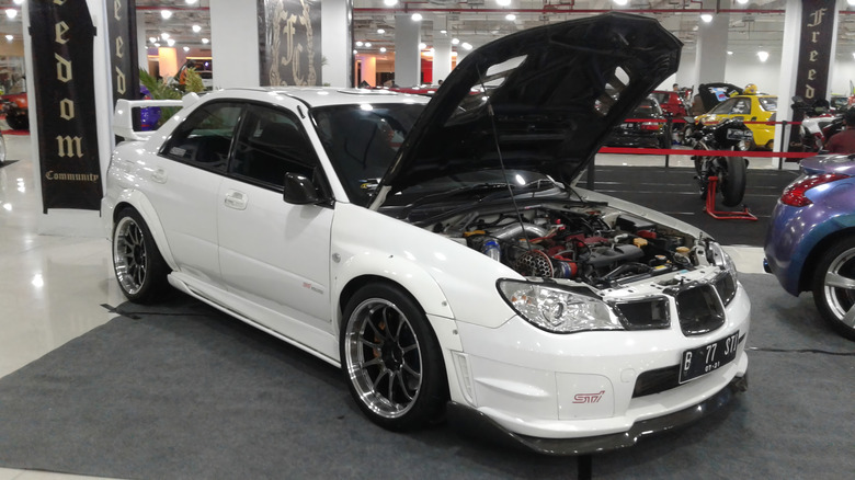 후드가 열려 있는 흰색 스바루 임프레자 WRX가 전시되어 있습니다.