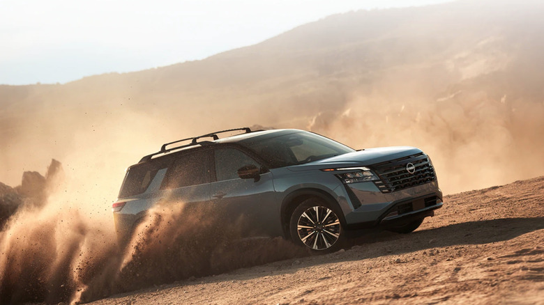 흙길을 오르막길을 달리는 회색 닛산 패스파인더