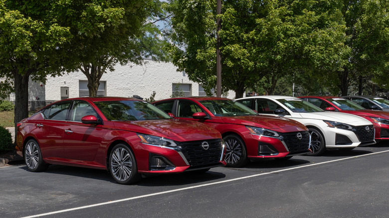 대리점에 주차된 빨간색과 흰색의 Nissan Altimas