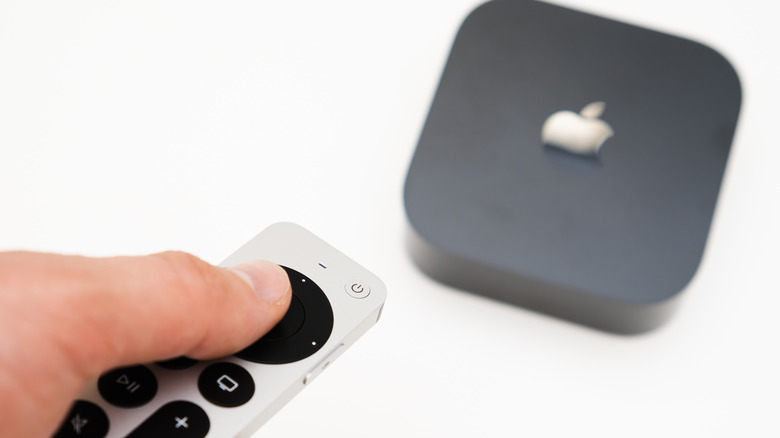 Apple TV 상자를 작동하기 위해 리모컨을 사용하는 사람