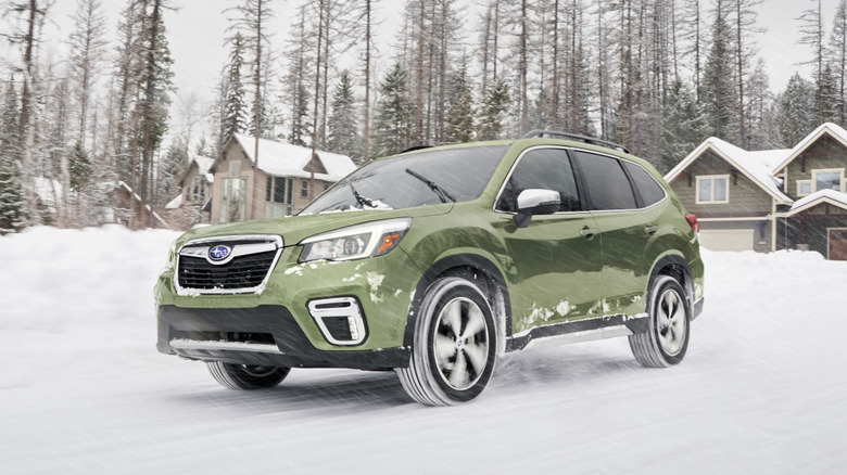눈 속에서 운전하는 올리브 그린 스바루 포레스터
