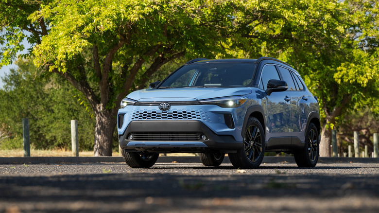 나무가 늘어선 거리에 주차된 2026 Toyota Corolla Cross Hybrid