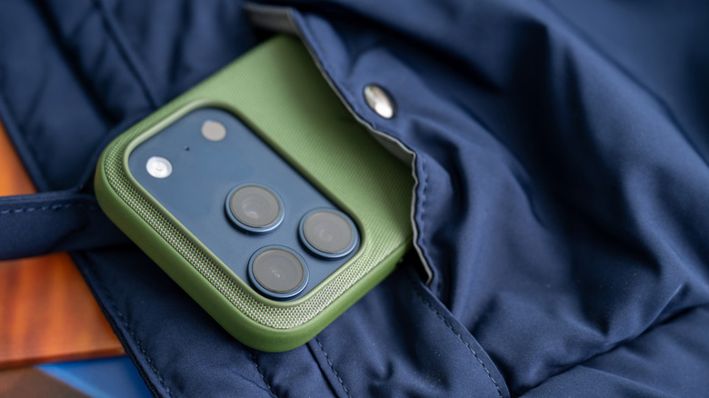 가방 주머니에서 튀어나온 Green TechWoven 케이스의 iPhone 17 Pro