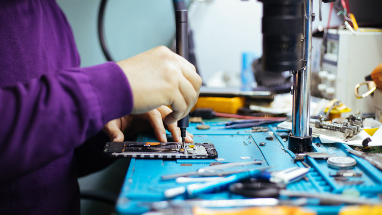 드라이버로 스마트폰을 분해하는 기술자