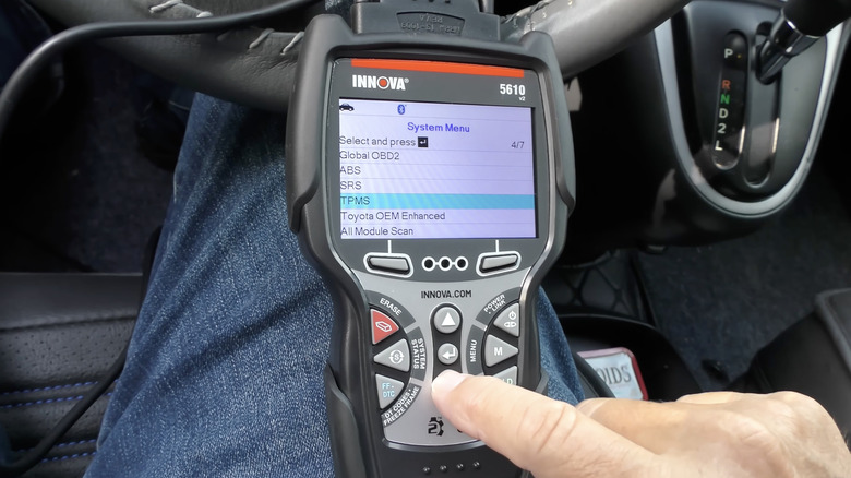 자동차 안에서 INNOVA OBD-II 스캐너를 들고 있는 사람.