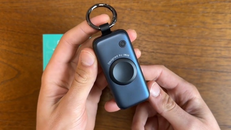 테이블 위에 Iniu SnapGo 미니 휴대용 충전기를 들고 있는 손