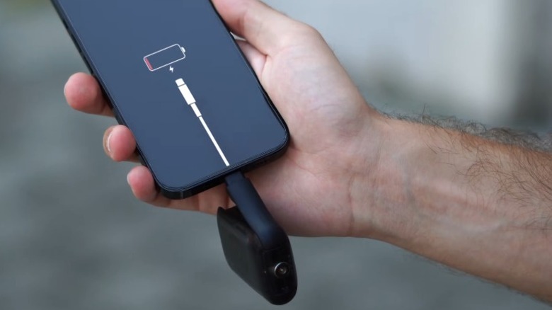 USB 포트에 연결된 Rolling Square Tau 2가 있는 죽은 스마트폰을 들고 있는 손