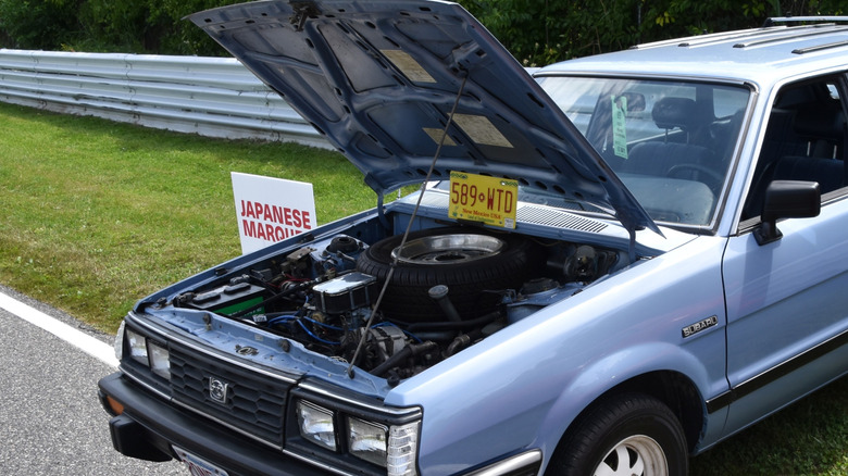 엔진과 스페어 타이어가 보이는 후드가 열려 있는 1984 Subaru GL