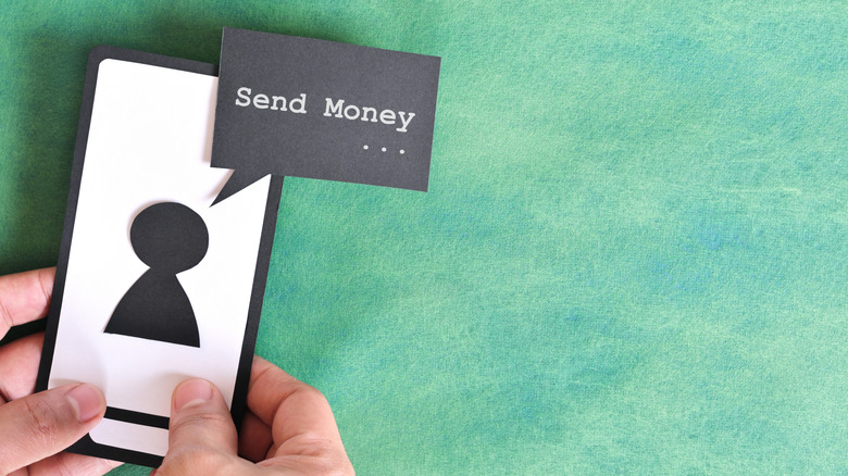 송금을 요청하는 문자가 표시된 휴대폰을 들고 있는 손