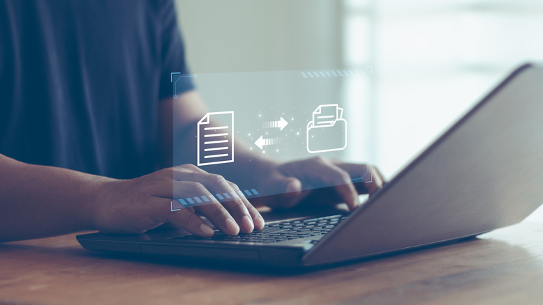 파일 전송 이미지가 겹쳐진 노트북으로 타이핑을 하고 있는 사람