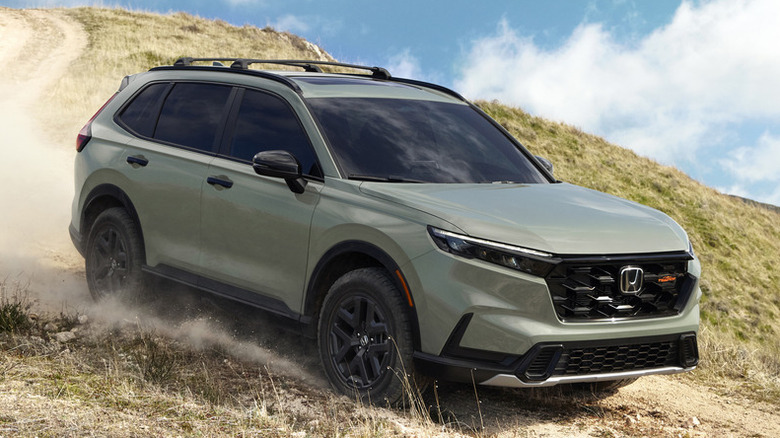 먼지가 많은 길을 달리는 Honda CR-V의 전면 3/4 뷰