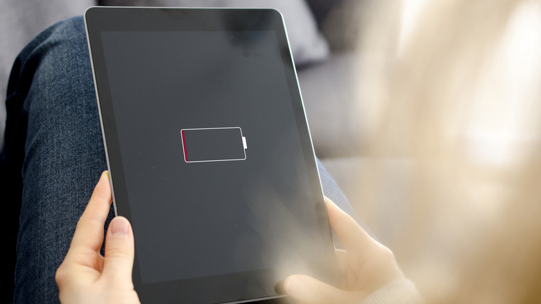 배터리 부족 경고 아이콘이 표시된 태블릿을 들고 있는 여성