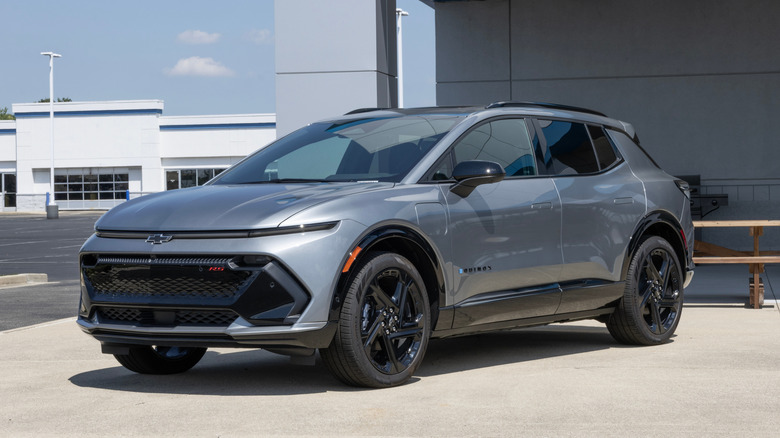 대리점 앞에 주차된 회색 Chevy Equinox EV RS의 전면 3/4 뷰.