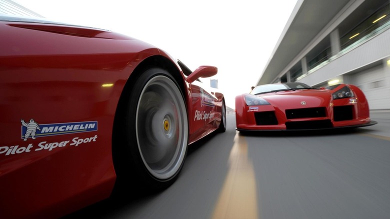 두 차량 모두 미쉐린 타이어 스티커가 부착된 빨간색 하이퍼카 2대가 트랙을 달리고 있습니다.