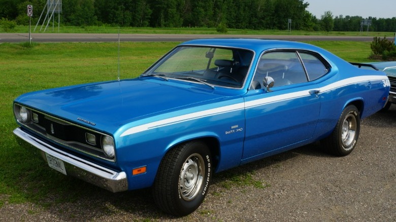 Blue Plymouth Duster 340이 시골 길 옆 자갈 위에 주차되어 있습니다.