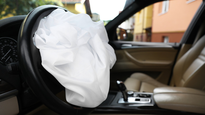 크림색 가죽 시트가 장착된 BMW로 보이는 차량 내부에 전개된 에어백