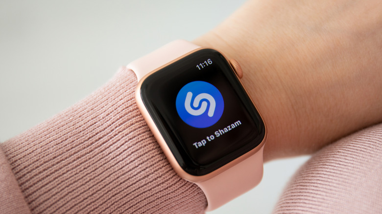 Shazam 로고가 표시된 여성 손목에 핑크색 밴드가 달린 Apple Watch