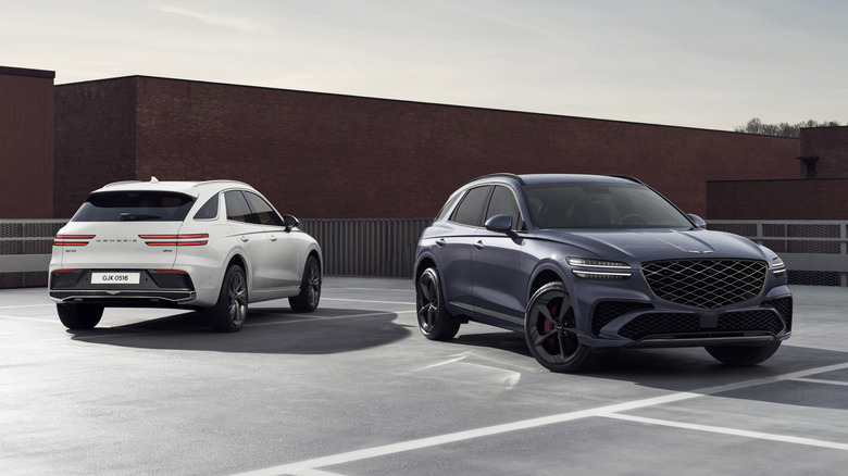 도심 야외 환경에 나란히 주차된 제네시스 GV70 SUV 두 대.