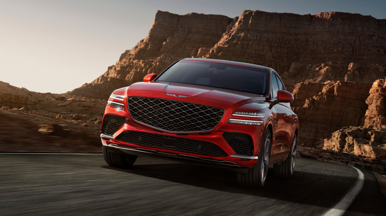 빨간색 제네시스 GV80 쿠페가 시골 사막 도로를 달리고 있습니다.