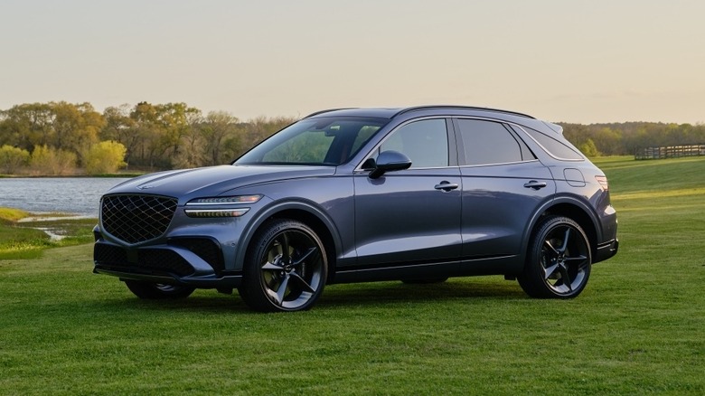 들판에 있는 청회색 제네시스 GV70, 전면 3/4 뷰, 화창한 날