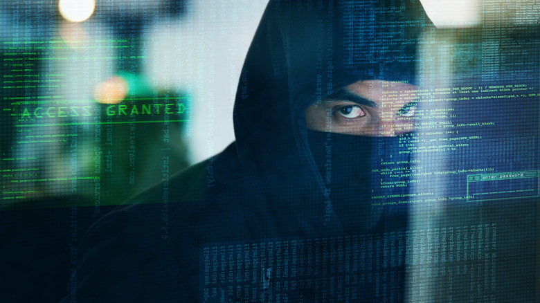 컴퓨터 코드 오버레이가 있는 발라클라바를 입은 의심스러운 남자