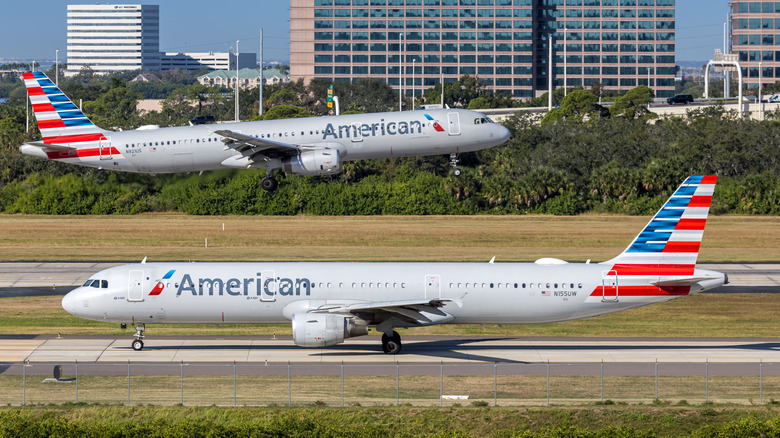 활주로를 활주하는 아메리칸 항공 비행기와 배경에서 이륙하는 아메리칸 항공 비행기