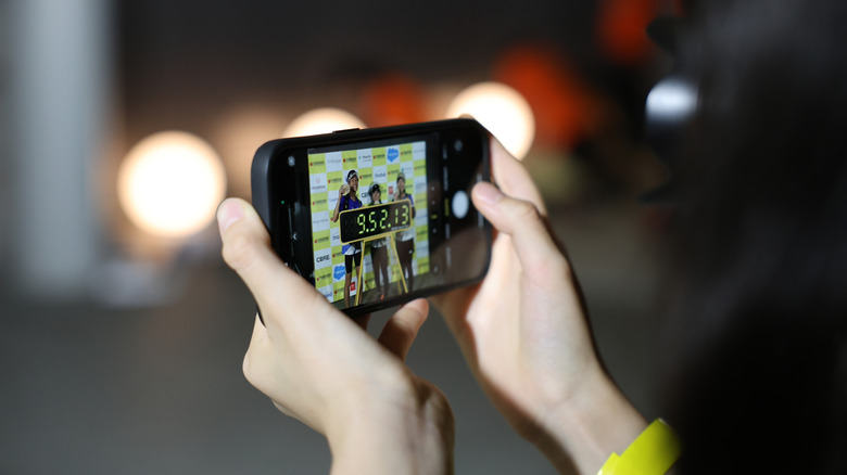 야외에서 iPhone 14 Pro Max를 들고 있는 손