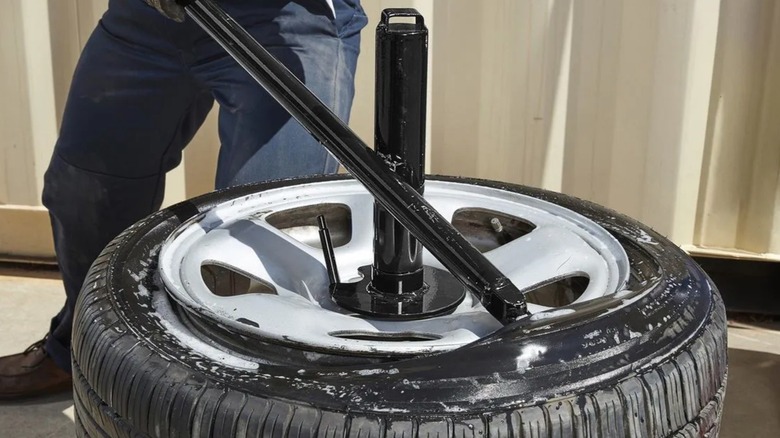 Harbour Freight의 타이어 체인저를 사용하여 타이어를 교체하는 사람